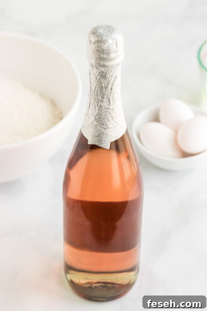 Ingredients for pink champagne cupcakes. A bottle of pink champagne with cupcake ingredients behind it. 