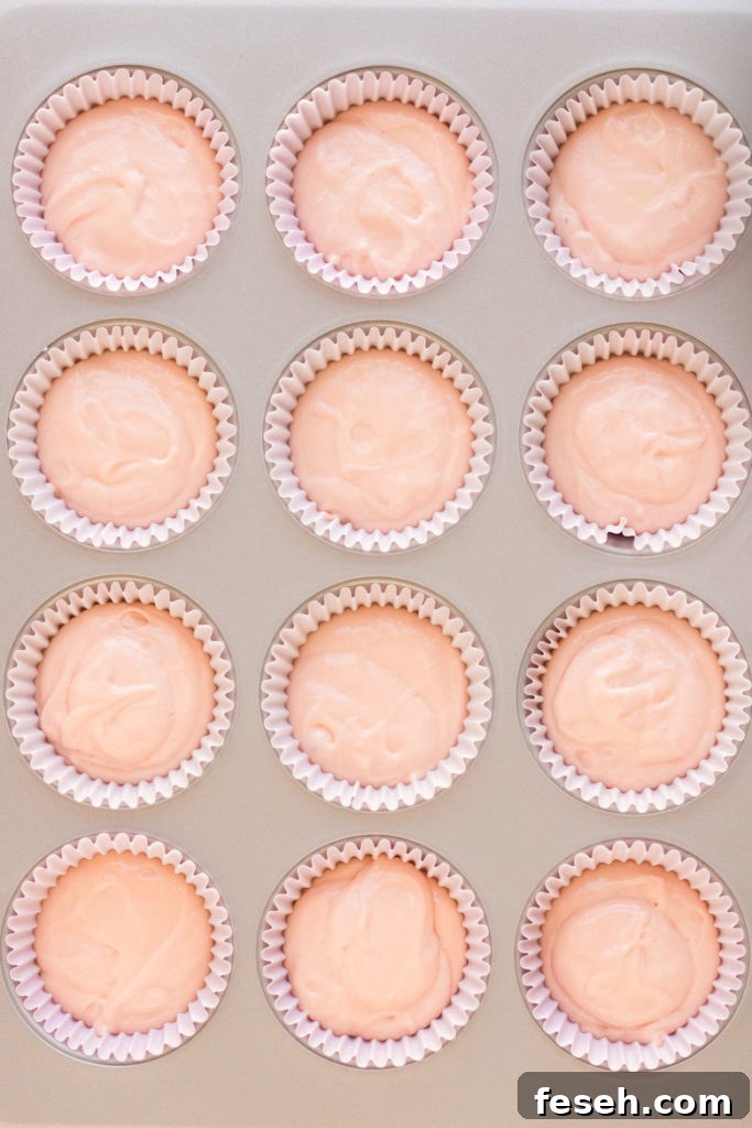 Raw pink champagne cupcake batter in a muffin tin with light pink liners. 