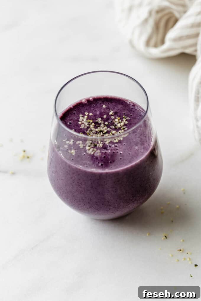 a glass of blueberry avocado smoothie on a marble board