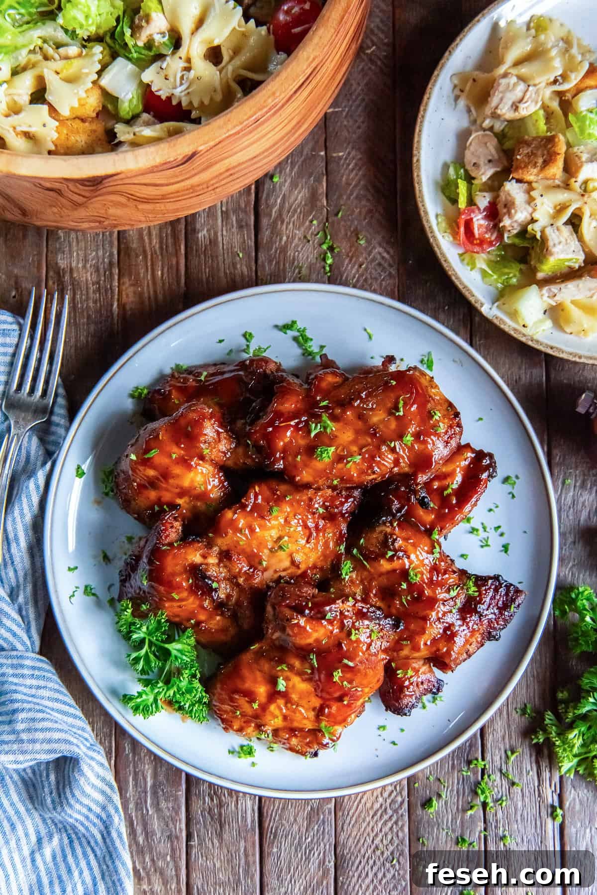 A plate filled with grilled chicken thighs next to a bowl of pasta salad.