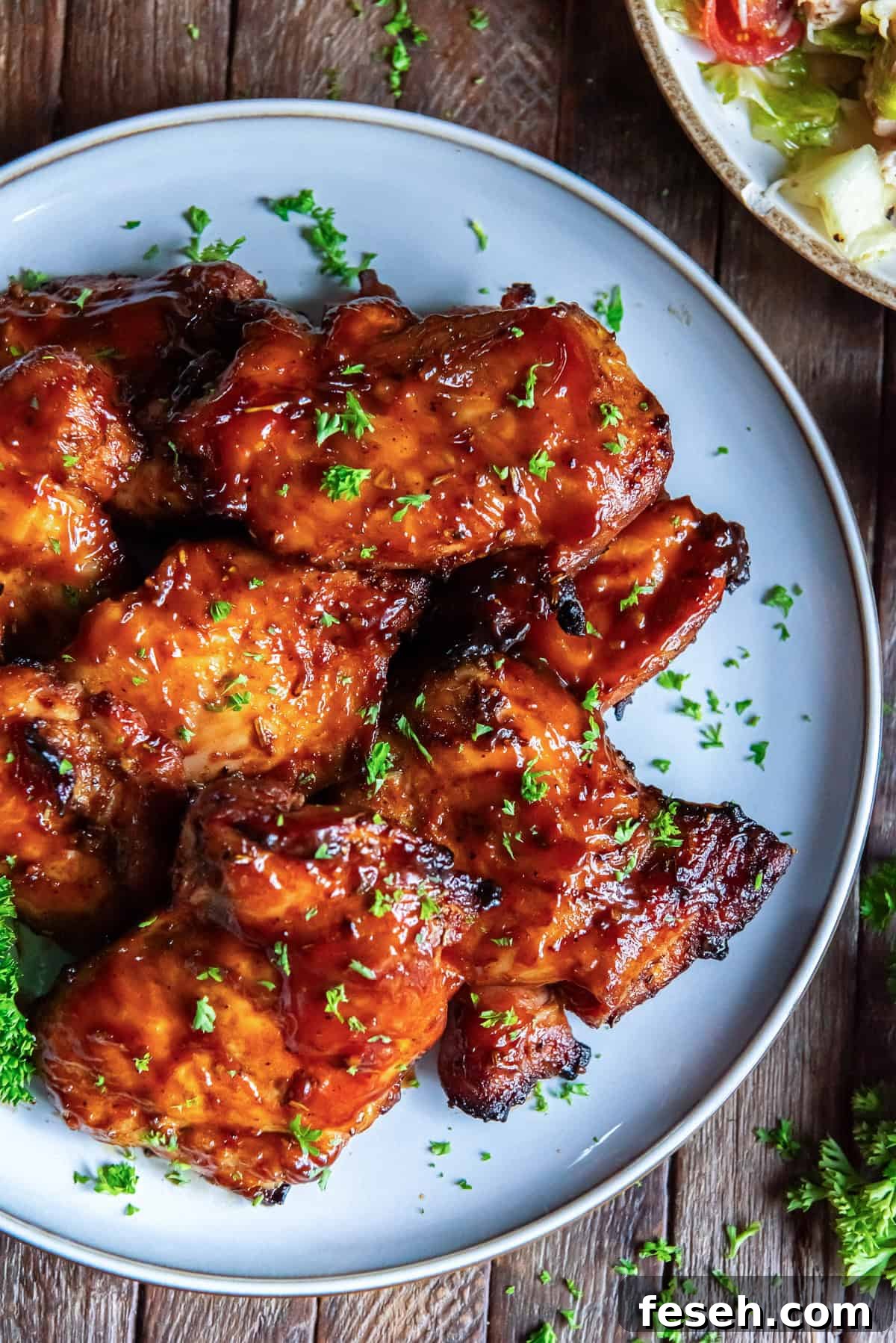 Grilled boneless chicken thighs on a white serving plate.