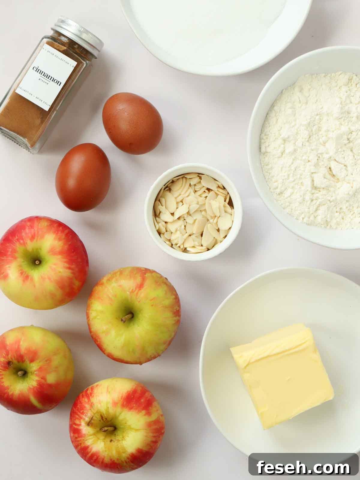 The ingredients for making an Apple Cake laid out on a white counter top.