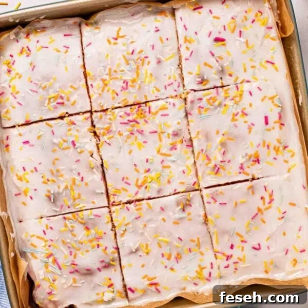 A square School Cake sponge with icing and sprinkles over the top, cut into squares.