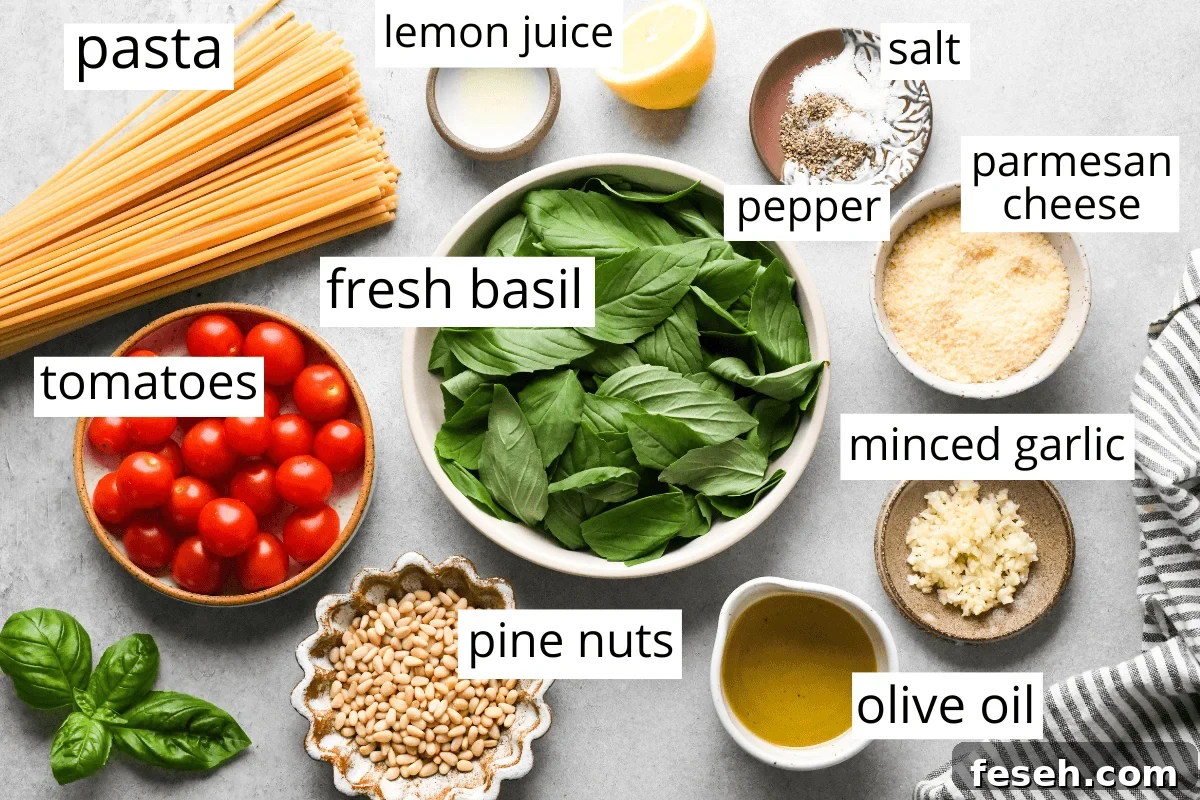 overhead photo of the ingredients in this pesto pasta recipe labeled and in bowls like fresh basil, tomatoes, pasta, minced garlic, olive oil, pine nuts, parmesan cheese and lemon juice.