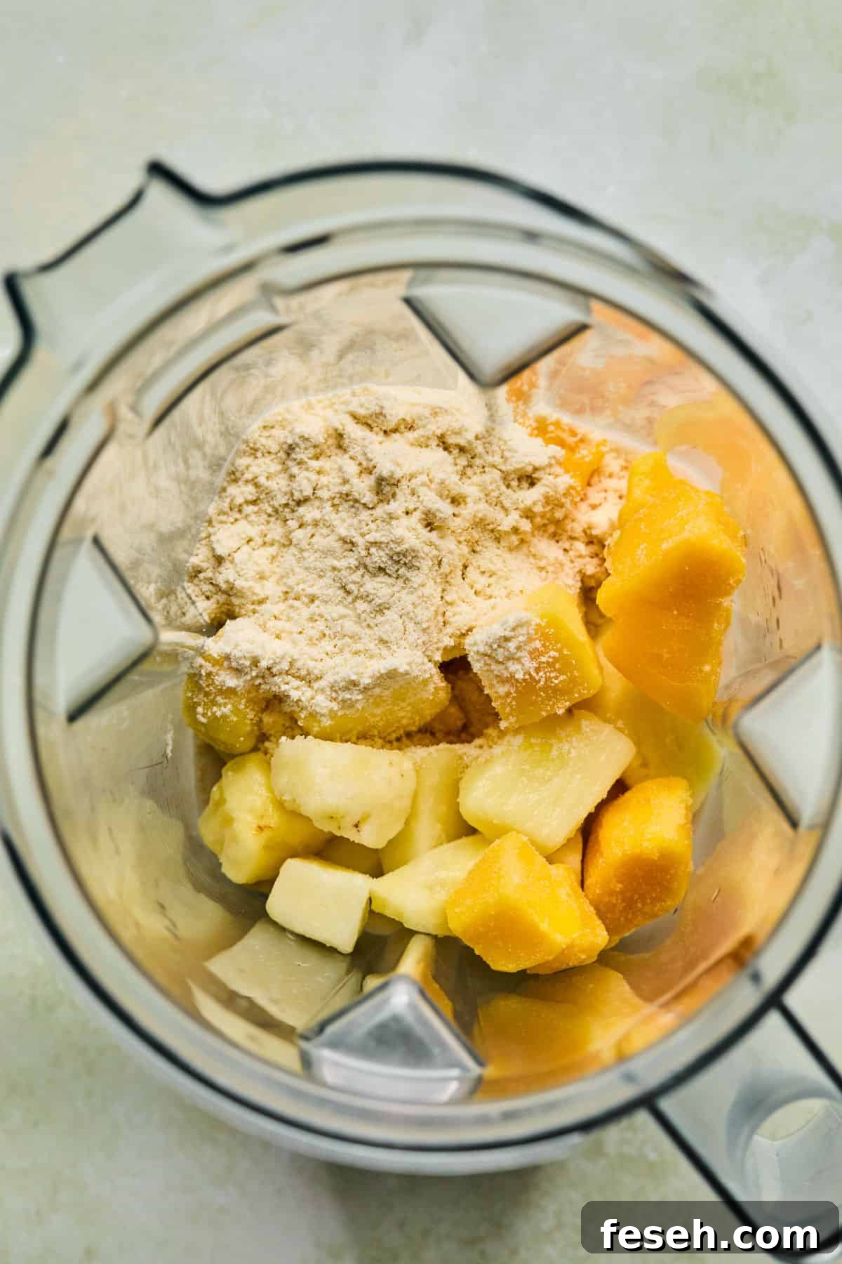 Vanilla protein powder and frozen fruit in a blender