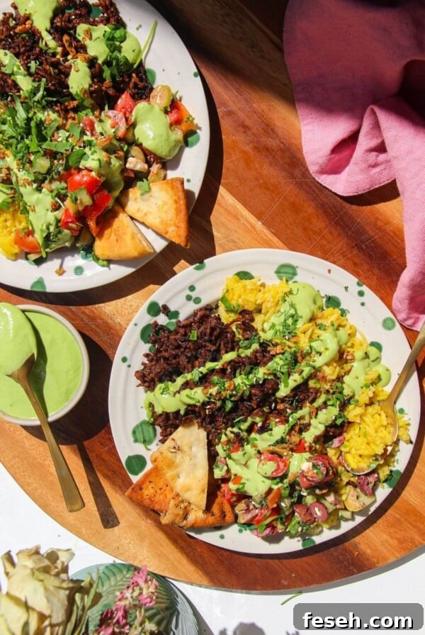 Two Mediterranean beef rice bowls, with green tahini sauce on the side.