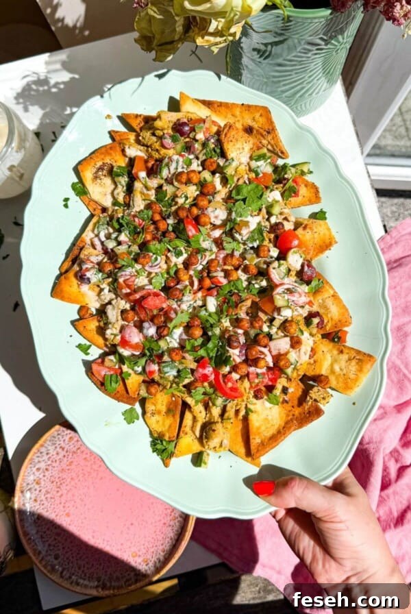 Hand holding platter of Greek pita nachos.