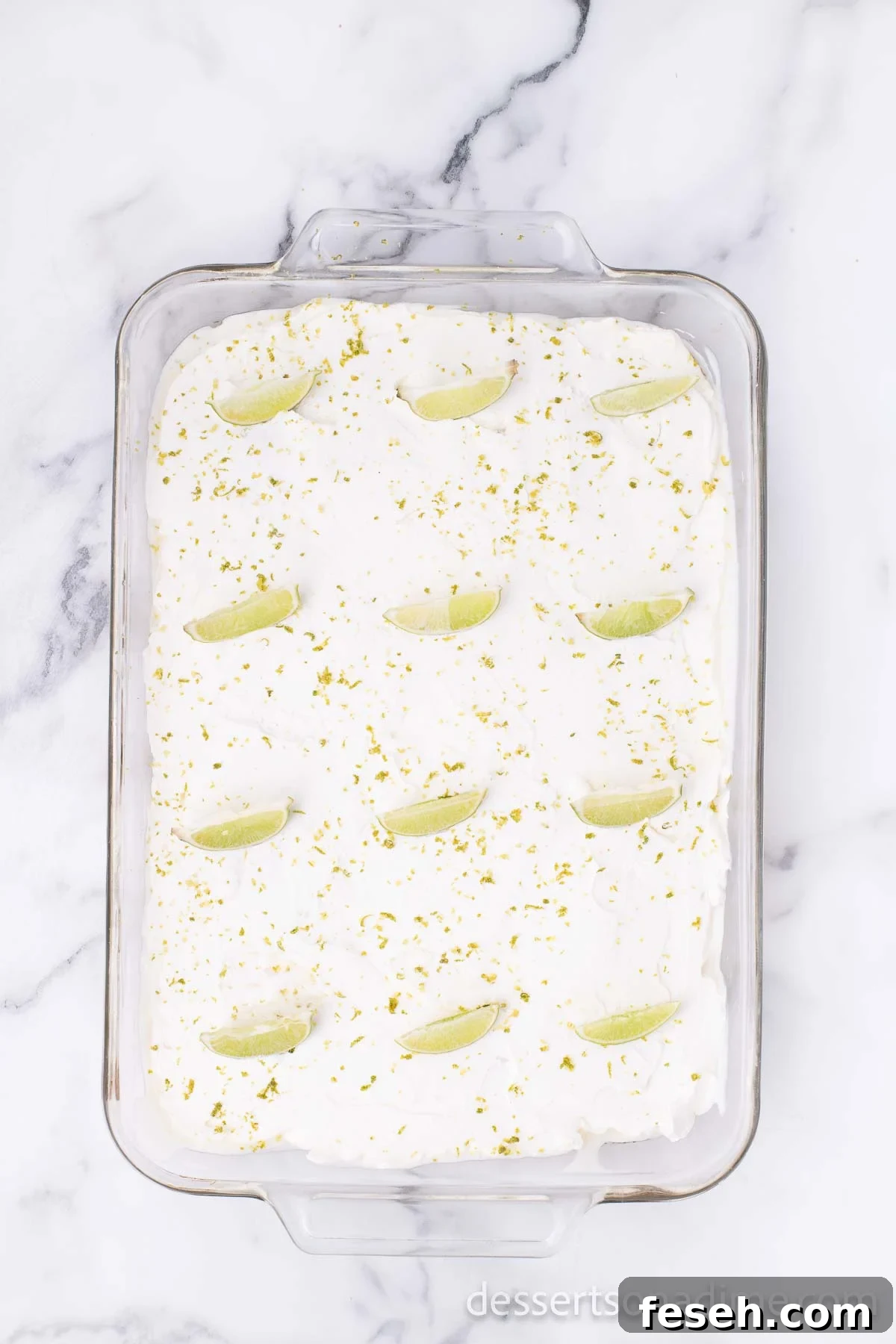 Margarita Poke Cake Recipe with Lime and Tequila 8 Topping spread on cake. Lime wedges arranged on cake.