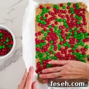 Pressing the dough into a pan and topping with M&Ms.