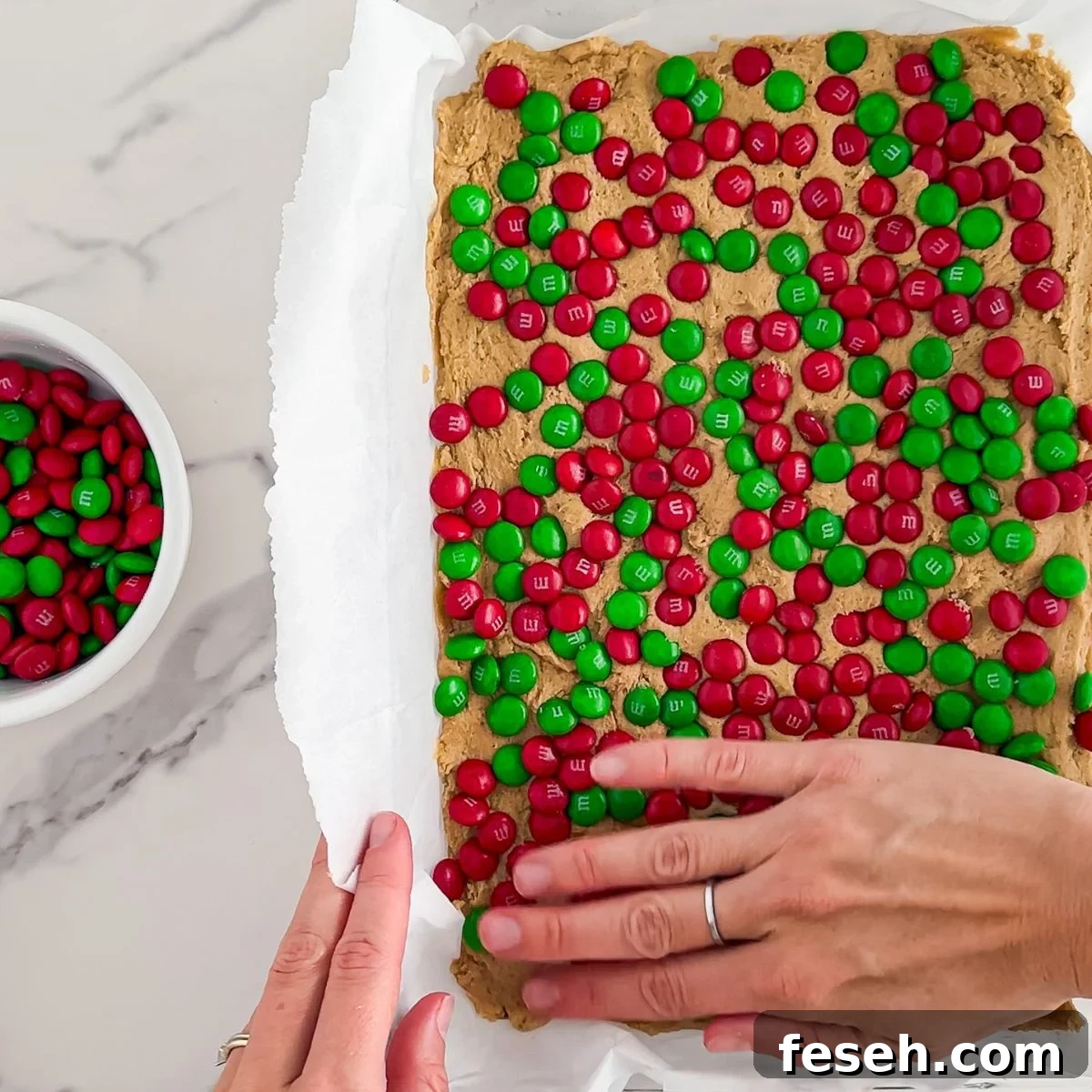 Pressing the dough into a pan and topping with M&Ms.