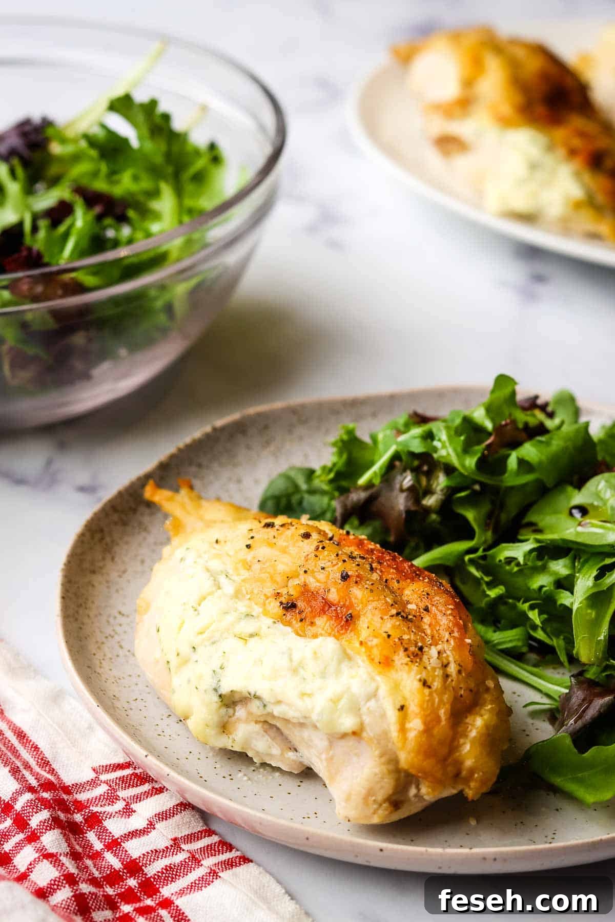 boursin chicken breast plated on a dish with a side salad.