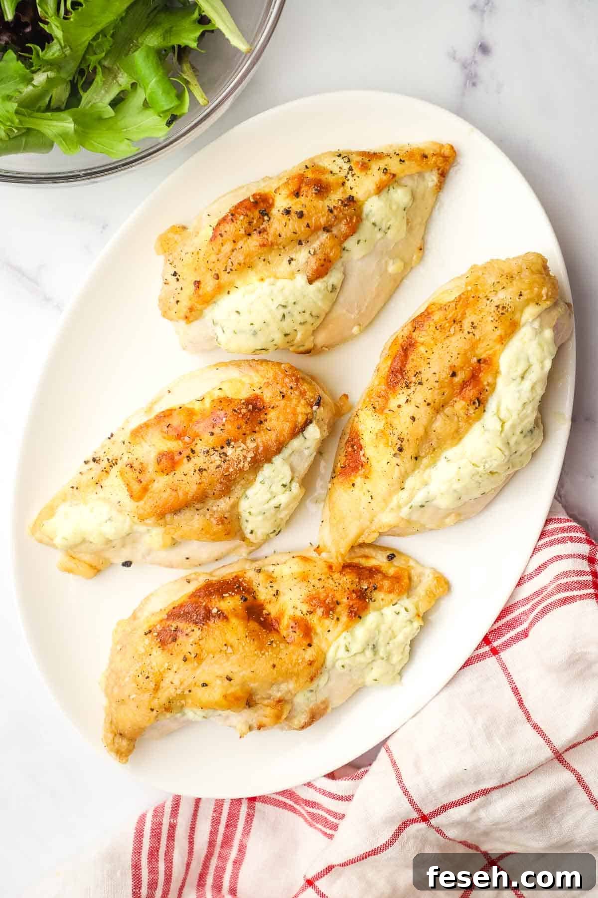 Four Boursin stuffed-chicken breasts on a white oval platter.