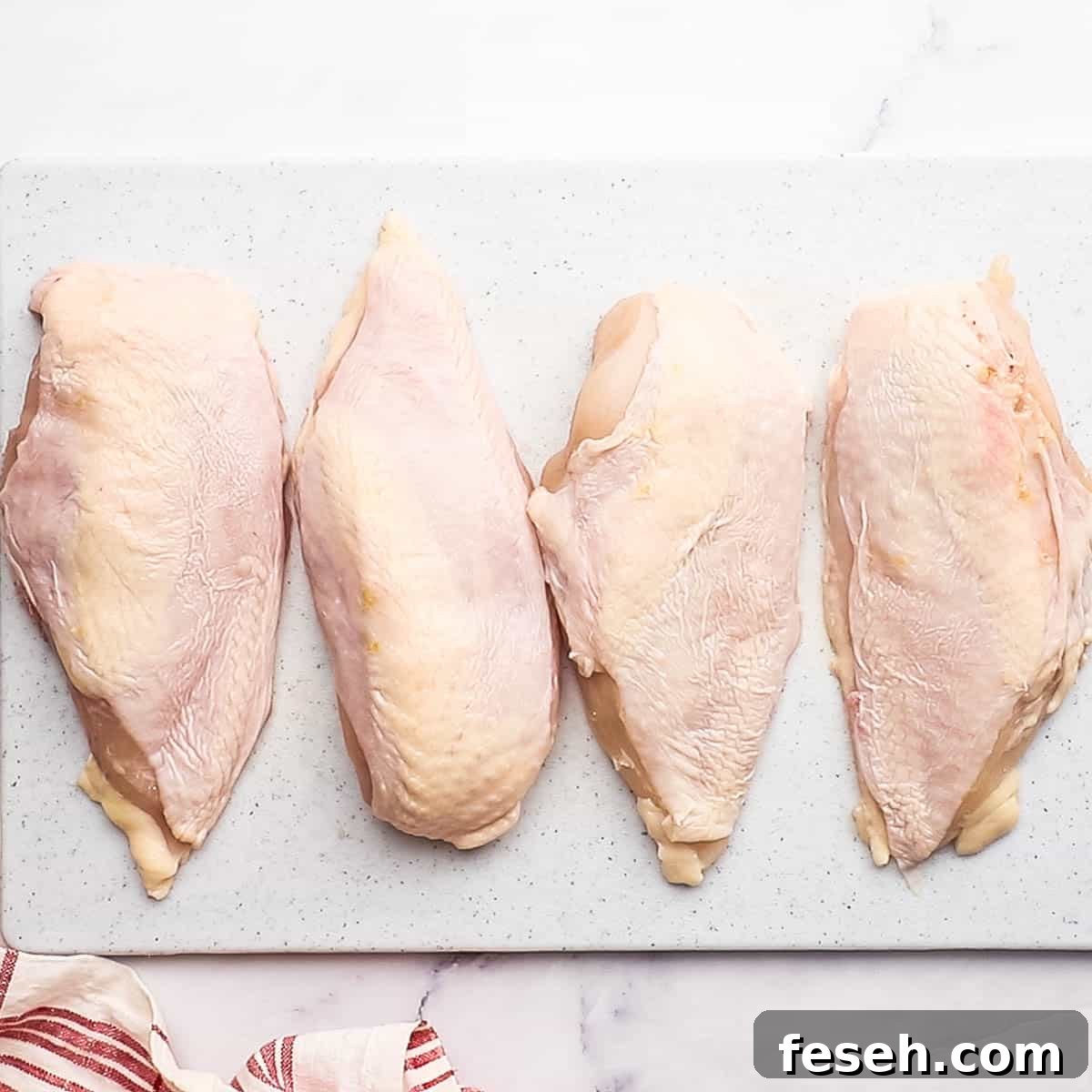 an overhead picture of 4 chicken breasts on a cutting board