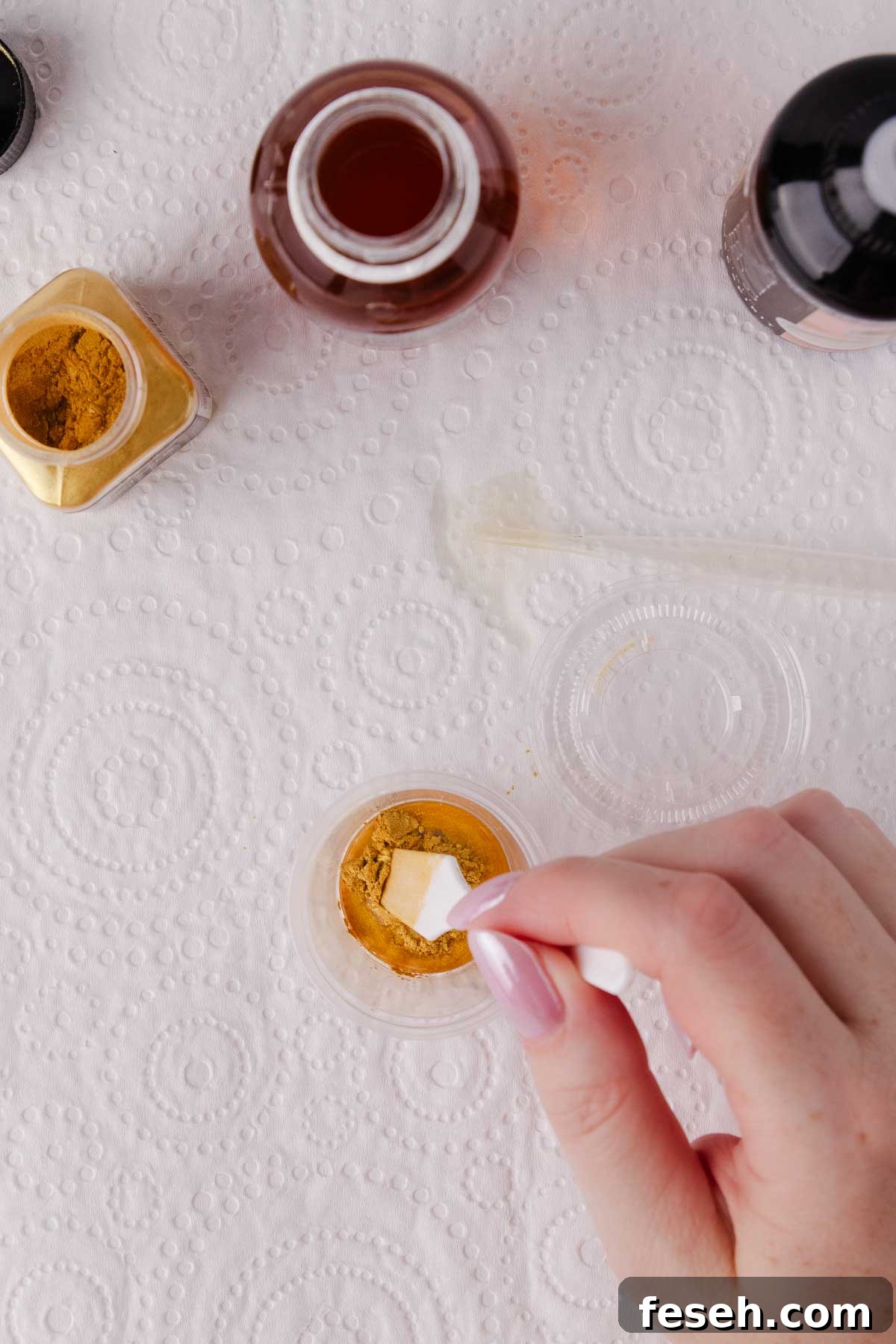 A hand gently stirring edible gold paint.