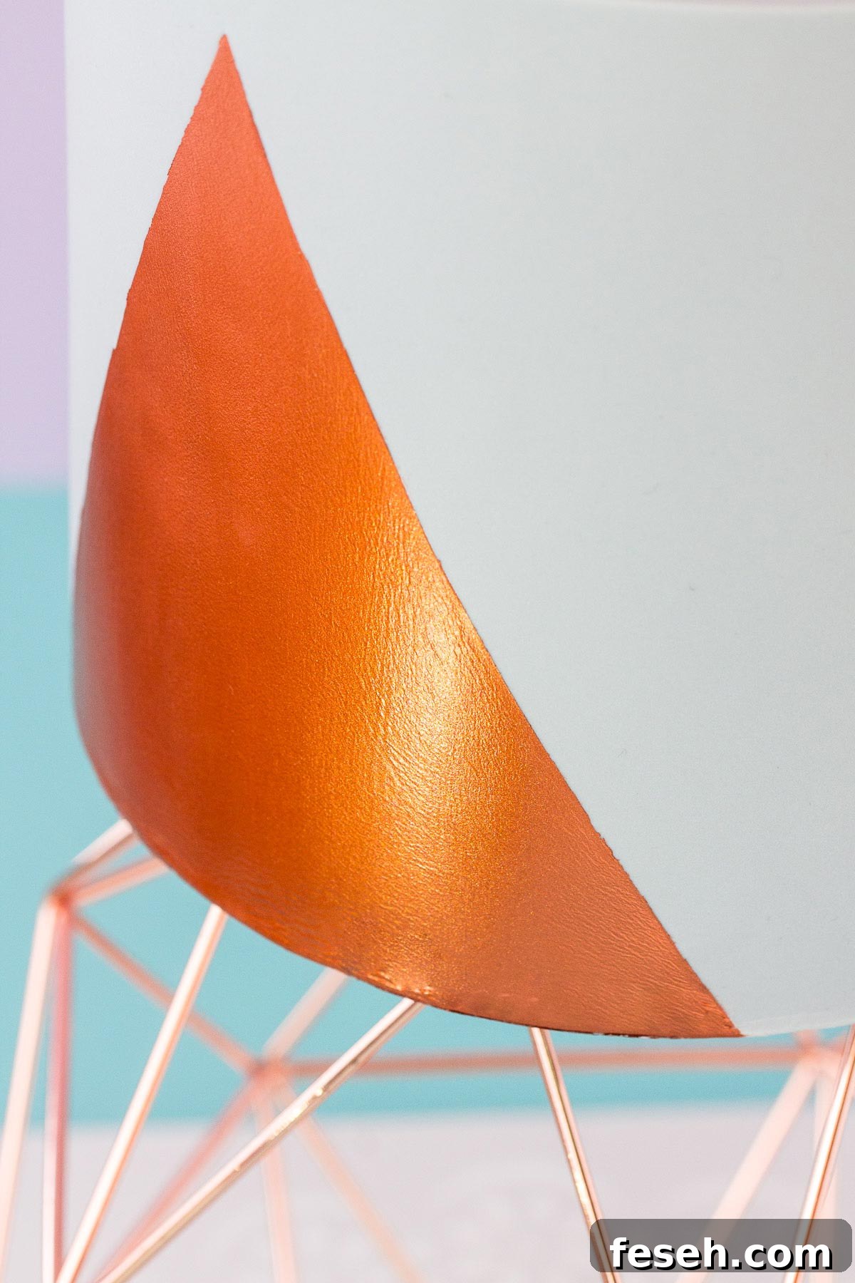 Close up of a grey fondant cake with a copper-coloured painted design.