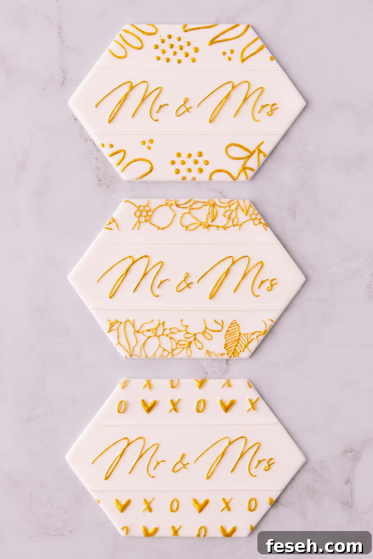 Three stamped fondant designs painted with gold paint saying "Mr & Mrs".