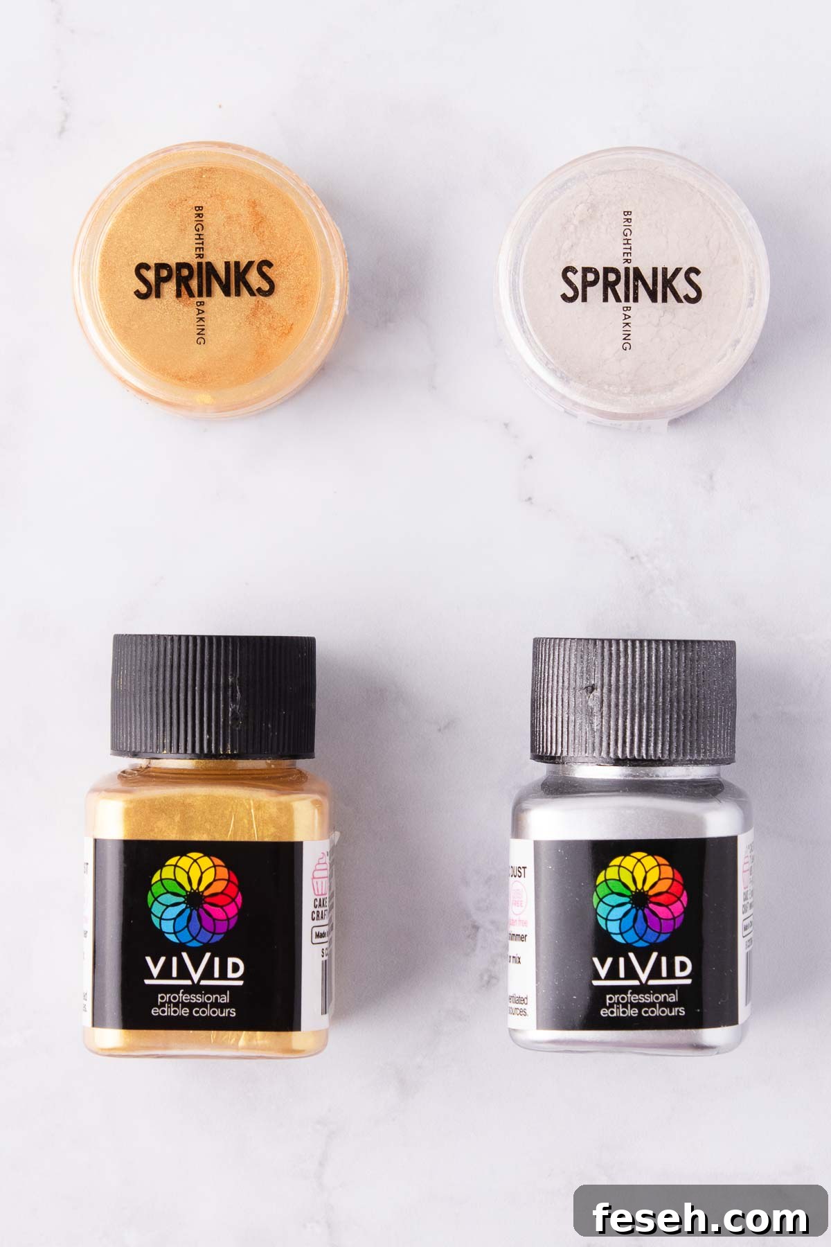 Small containers of edible gold lustre dust on a grey marble background.
