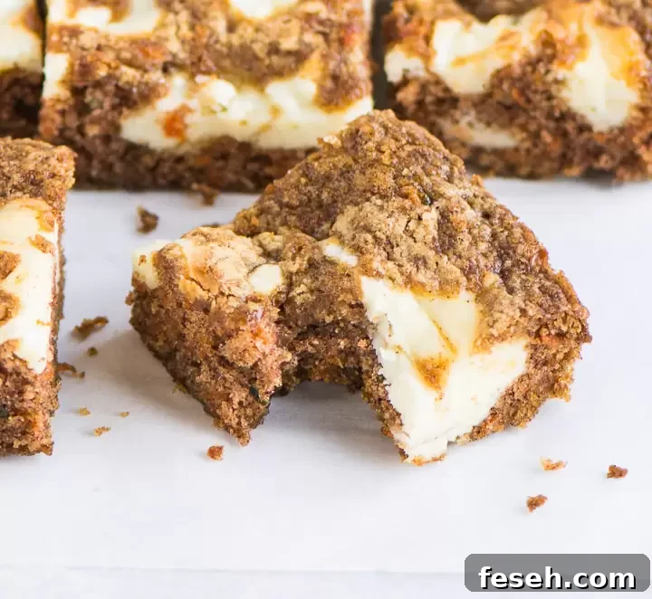 Chewy Carrot Cake Bars with Cream Cheese Frosting 5 carrot cake bar with a bite taken out of it in front of other bars