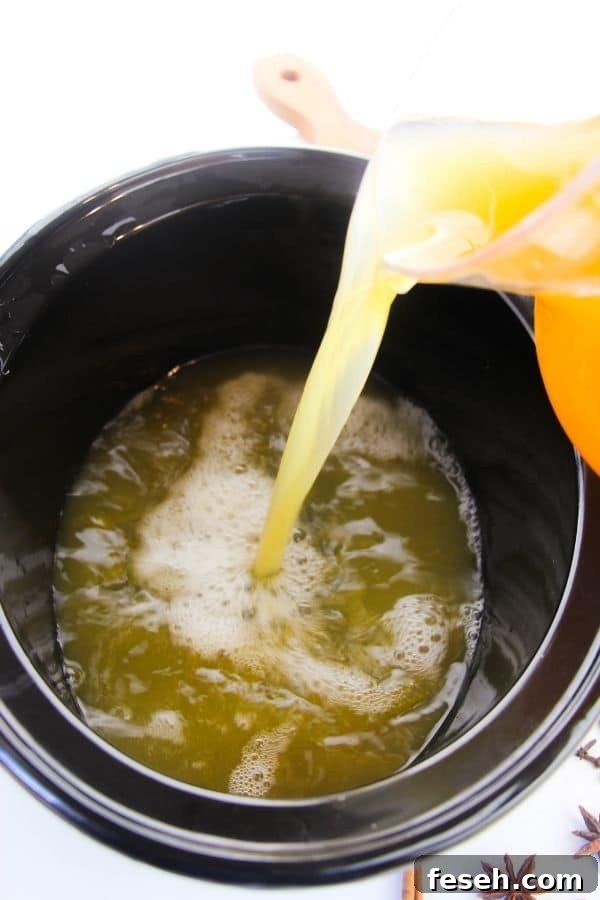 apple cider pouring into crockpot