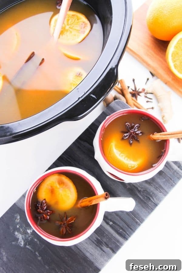 cups of cider and slow cooker with cider in it