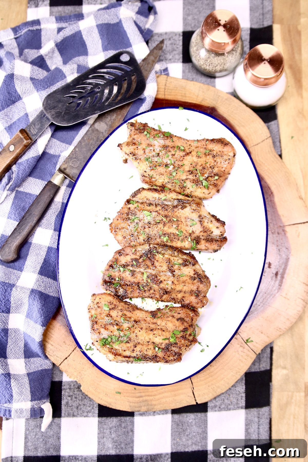 platter of grilled pork chops with salt & pepper shakers on a wood board
