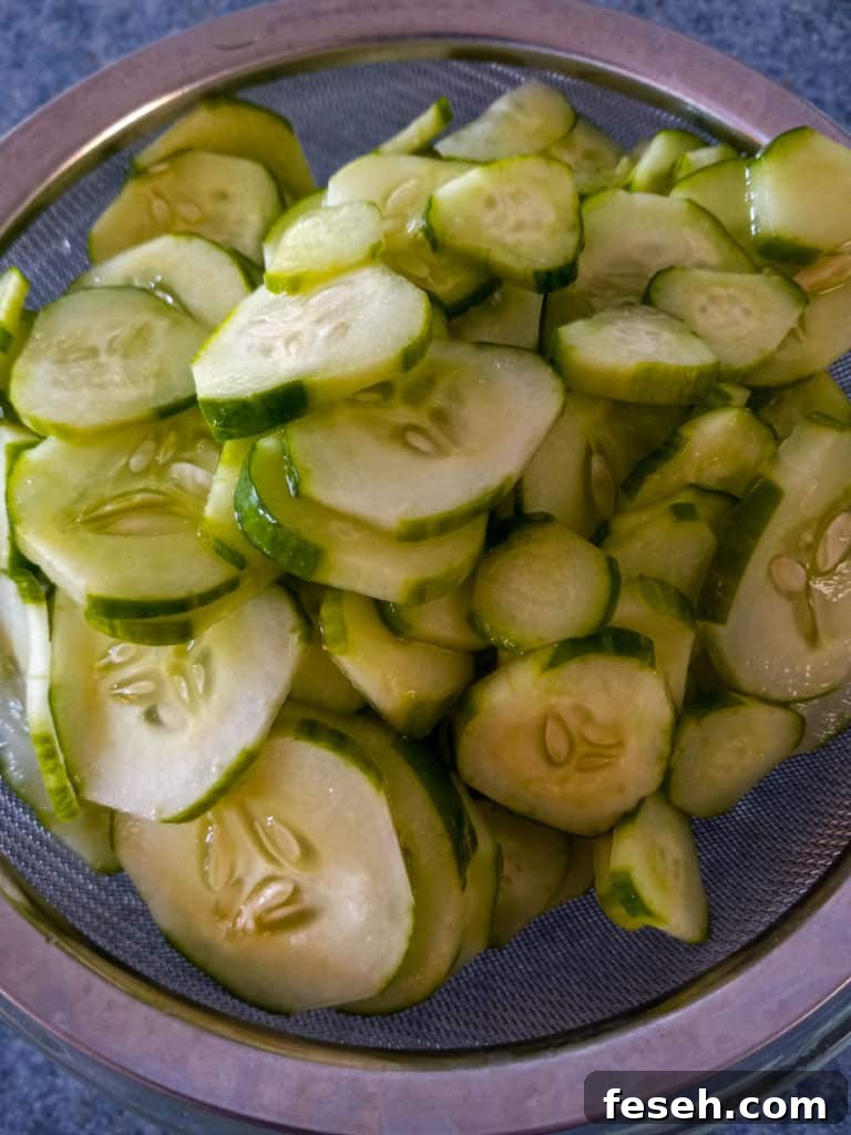 salted sliced cucumbers in a strainer.