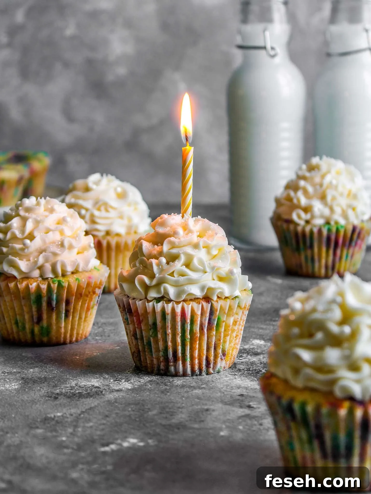 Classic Funfetti Cupcakes with Vanilla Frosting 2 frosted funfetti cupcakes with lit candle in one cupcake