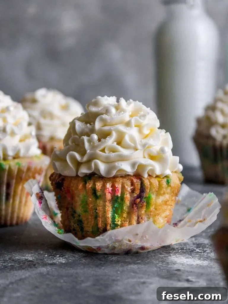 Classic Funfetti Cupcakes with Vanilla Frosting 4 frosted funfetti cupcakes on table with cupcake unwraped (1)