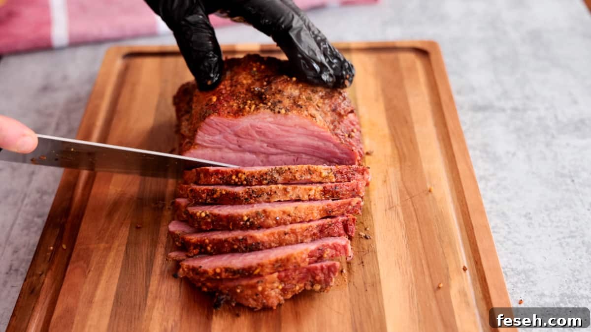 Smoked Corned Beef Recipe for Tender, Flavorful Brisket 9 Smoked corned beef being sliced on cutting board with knife.