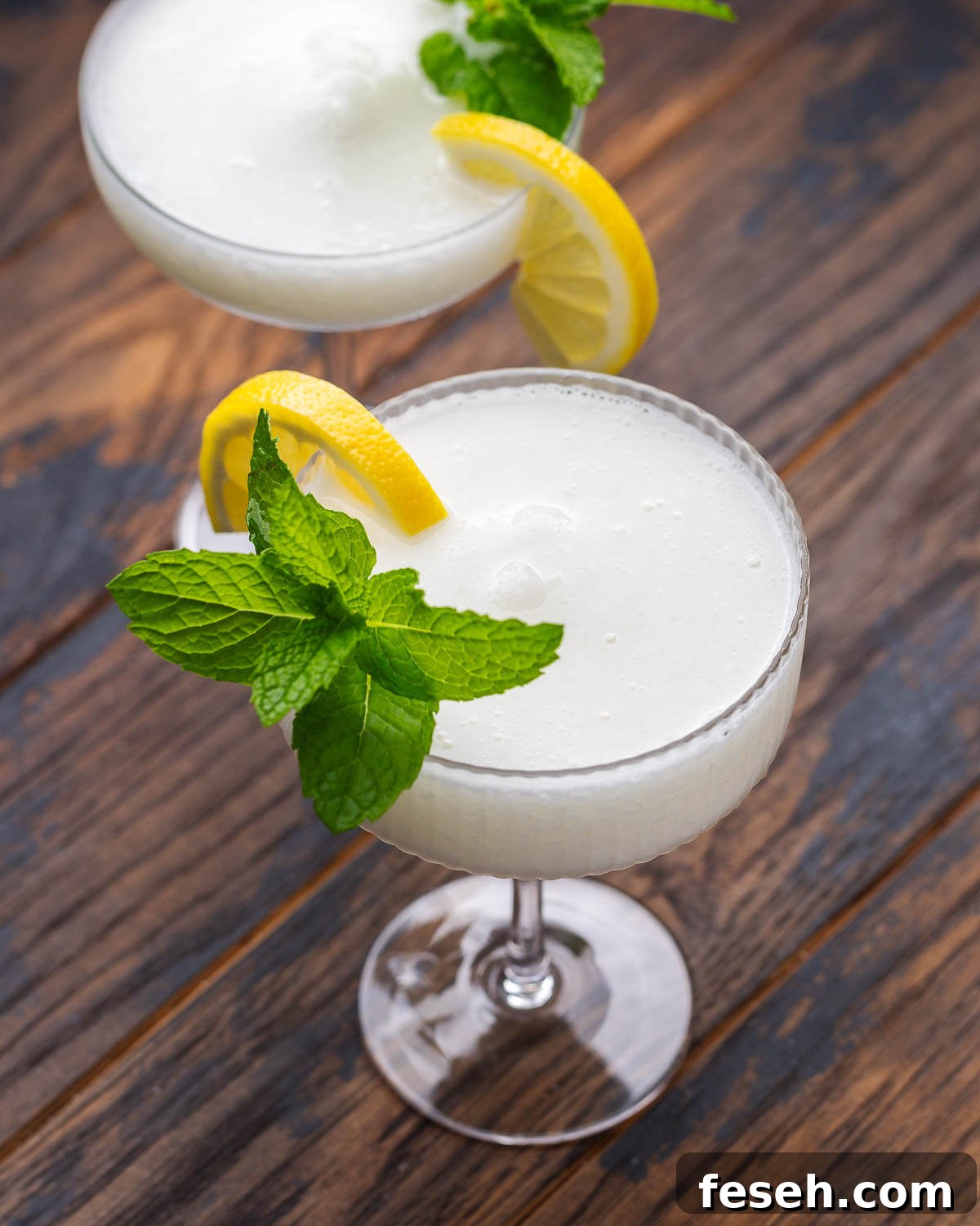 Sgroppino: Italian Lemon Sorbet and Prosecco Cocktail 5 Two sgroppino cocktails in coupe glasses with mint and lemon garnish.