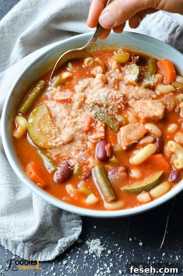 Hearty Chicken Minestrone Soup with Vegetables 9 Healthy Chicken Minestrone Soup in a bowl served with grated parmesan cheese & a spoon