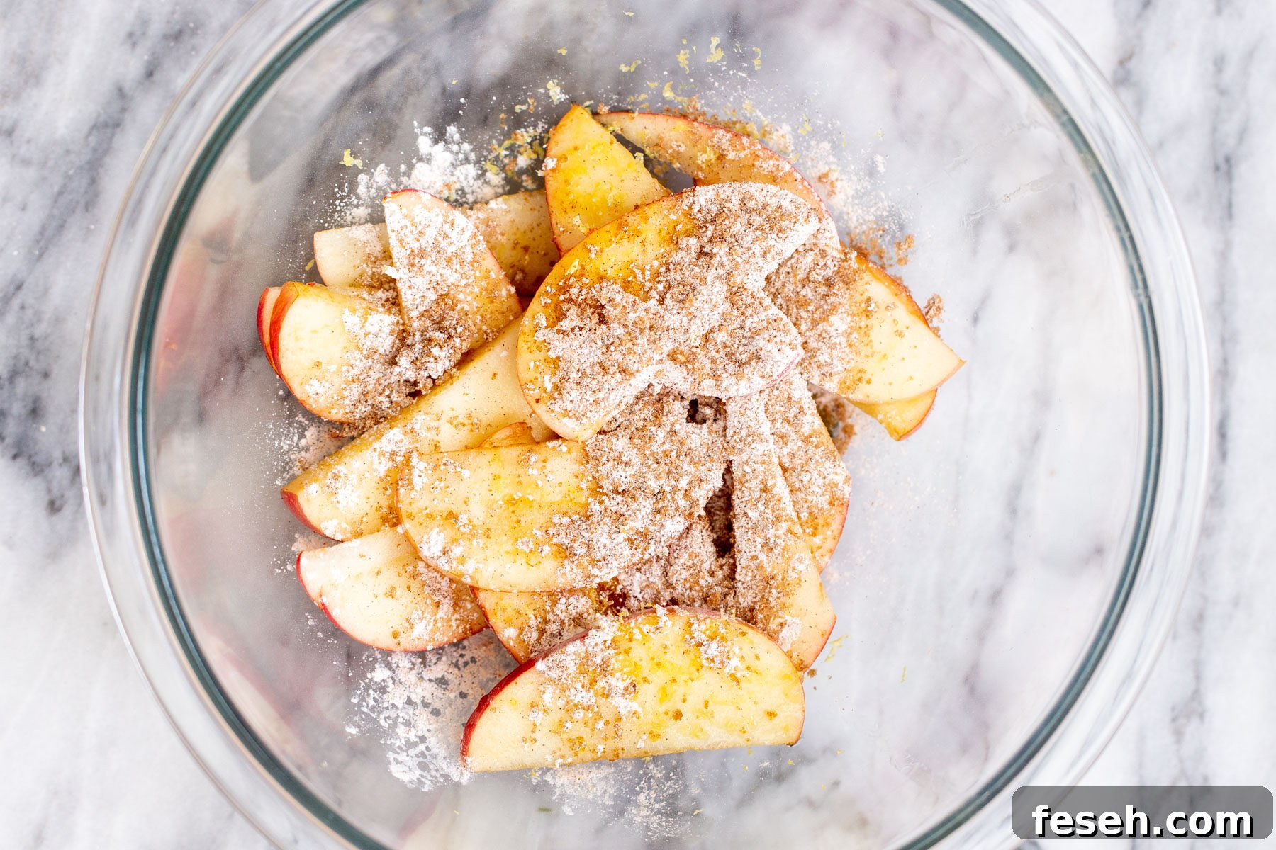 Vegan Apple Pie Bars with Cinnamon Streusel 6 apple slices in a glass bowl being mixed with brown sugar and cornstarch