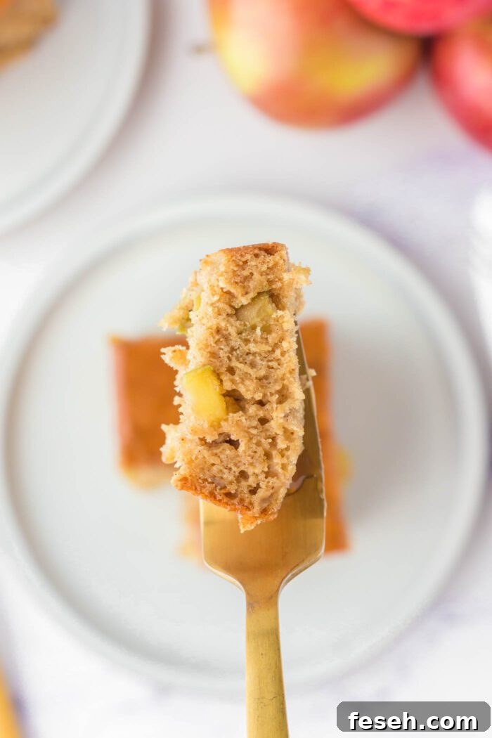 Moist Vegan Apple Cake with Cinnamon Glaze 13 A fork with a piece of caramel apple cake on it held over a square of apple cake on a small plate.