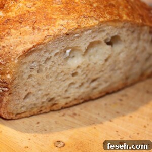 No knead bread sliced in half on a wooden work surface