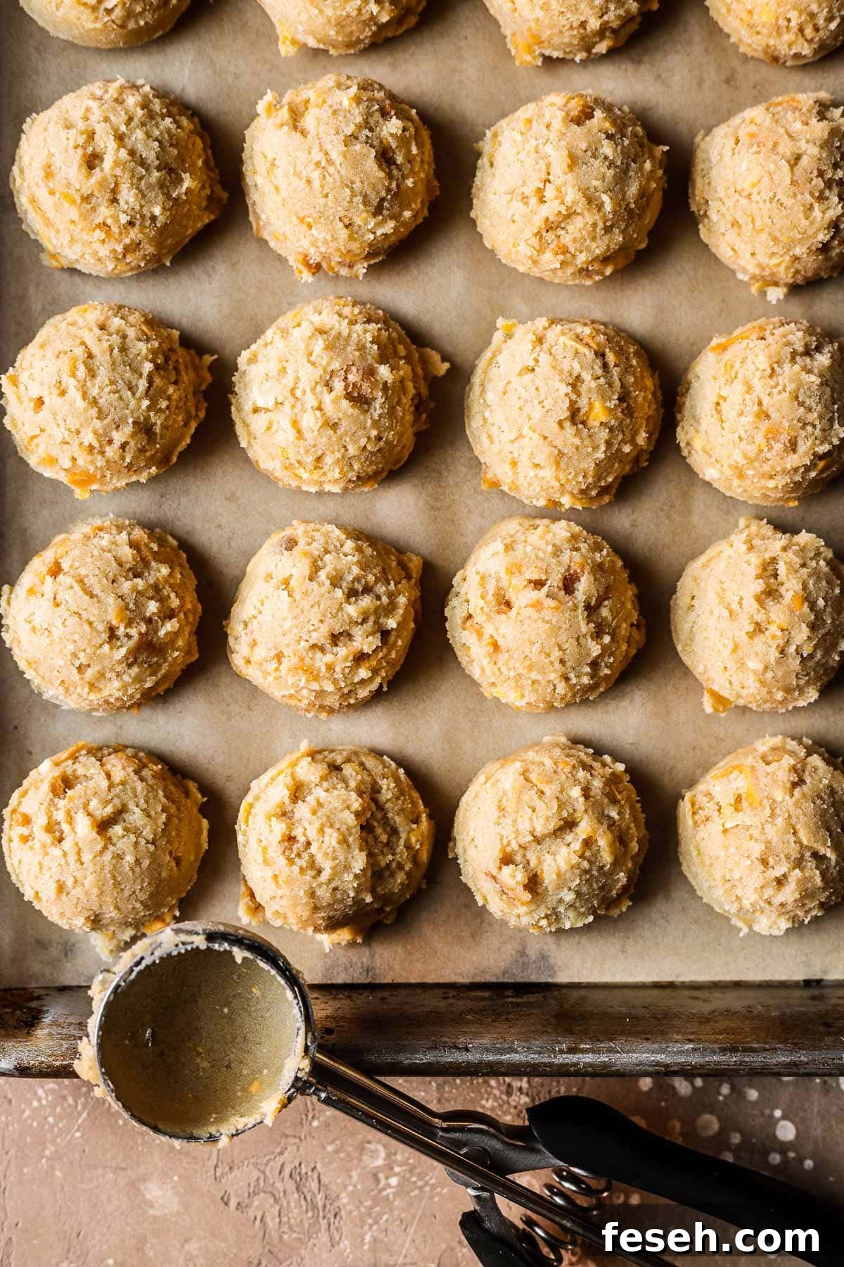 Tropical Mango Cookies with Coconut Glaze 11 Scoops of mango cookie dough on a parchment lined baking sheet.