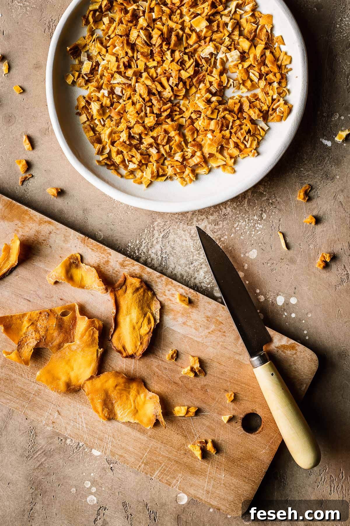 Tropical Mango Cookies with Coconut Glaze 6 A plate of diced dried mangos alongside a wooden cutting board, paring knife and dried mango cheeks.