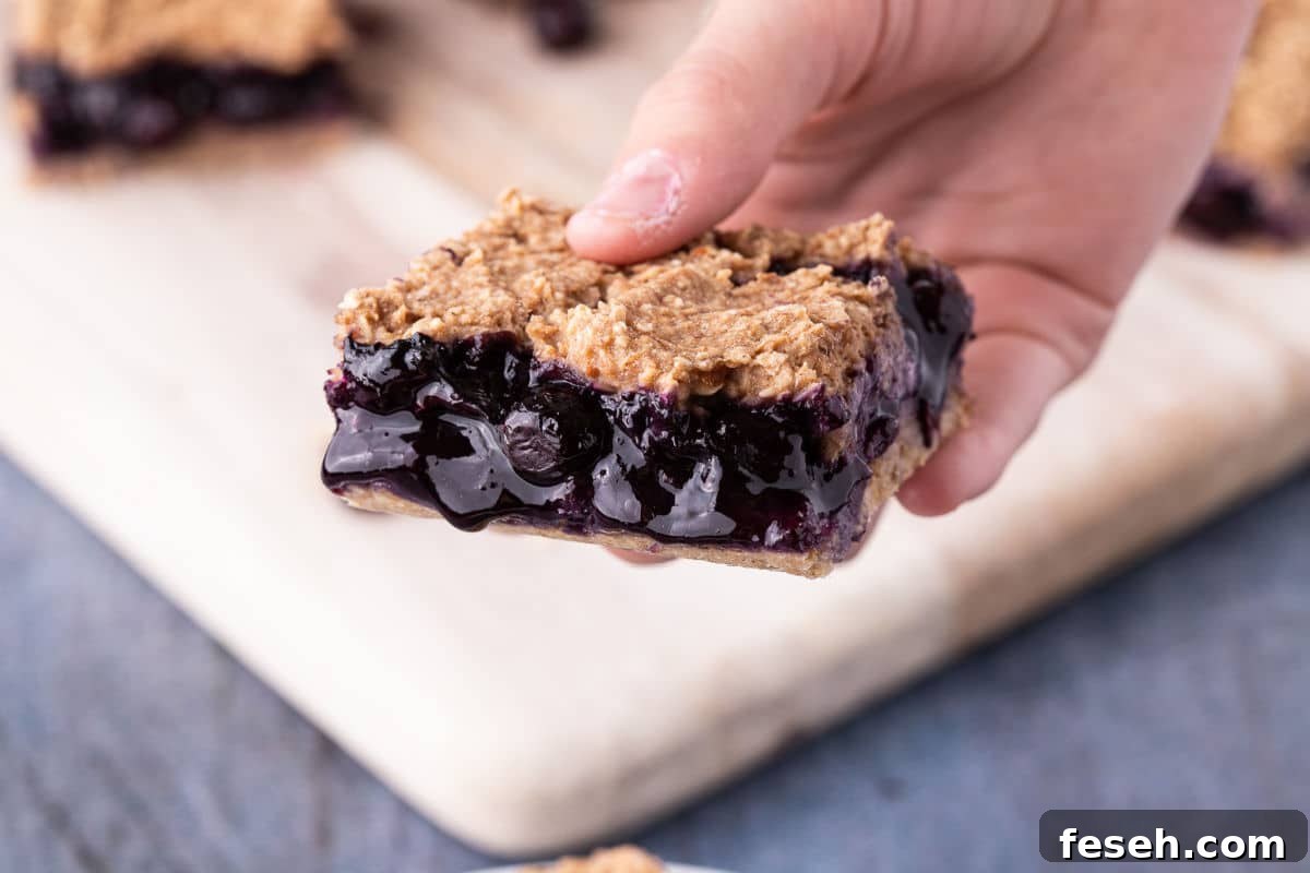 No Added Sugar Blueberry Pie Bars Recipe 3 Hand holding a blueberry bar.